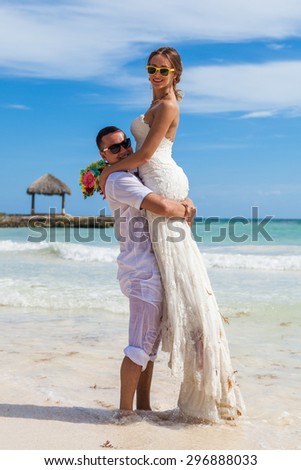 Guy holds girl on hands. Ocean beach.