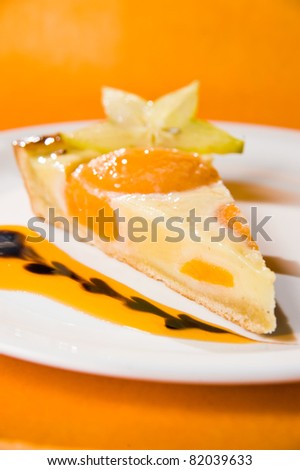 A piece of peach cheesecake on a plate. Orange background. Shallow depth of field.
