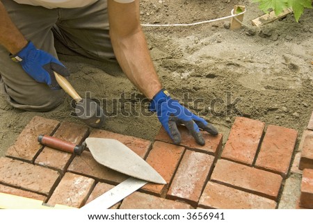 man laying brick patio