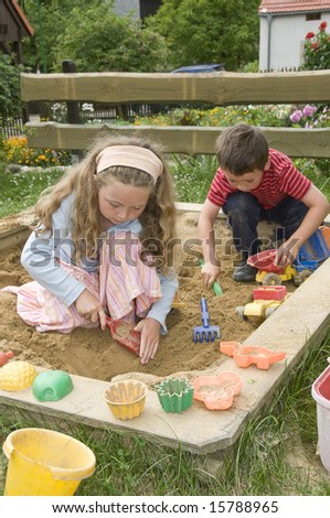 boy and girl playing in sand box