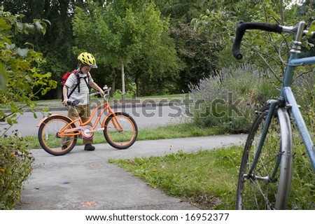 boy with yellow helmet and orange bicycle getting ready for a ride