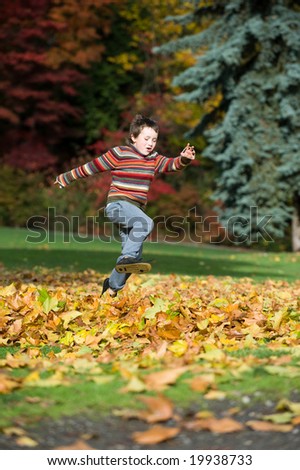 boy jumping in pile of leaves
