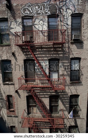old brick apartment building with fire escape and graffiti., new york city