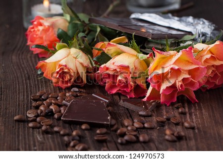 Bunch of orange roses with dark chocolate and coffee beans on old wooden table