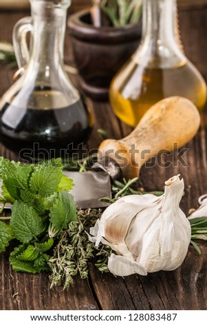 vintage knife with garlic, mint and thyme, oil and vinegar in vintage bottles on old wooden table