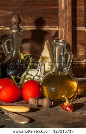 garlic, wet red cherry tomatoes and cheese parmesan on wooden table with olive oil in vintage glass bottle