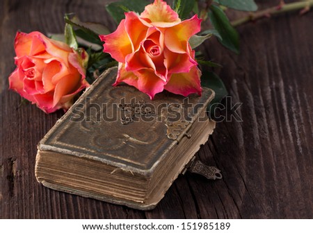 wet orange roses on old brown wooden table with old bible book