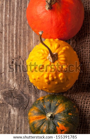 Top view on three colorful mini pumpkins on old wooden table