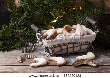 Homemade sugar cookies crescent served in basket with vintage cookie-cutters near christmas tree over old wooden table