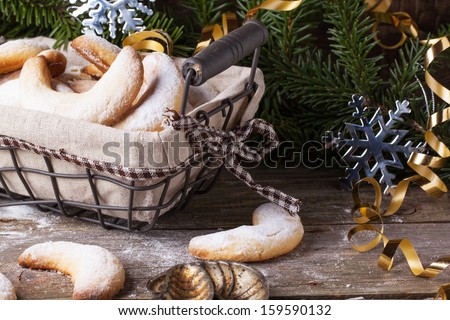 Top view on homemade sugar cookies crescent served in basket with vintage cookie-cutters and gifts near christmas tree over vintage teatured background