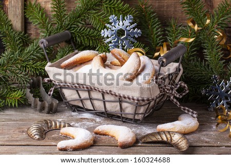 Homemade sugar cookies crescent served in basket with vintage cookie-cutters near christmas tree over old wooden table