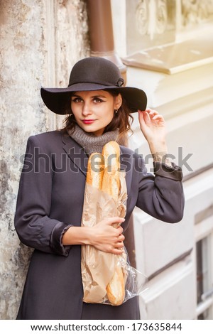 beautiful young woman in retro french style on old town street with bread and tattoo on arm