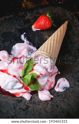 Wafer cone with strawberry ice cream with fresh strawberries and mint over black table. See series