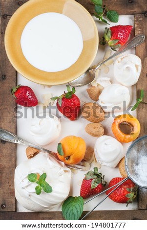 Homemade meringue with apricots, strawberries, almonds and cream. Ingredients for dessert Eton mess. Top view.