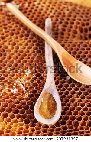 Vintage wooden spoon with honey over honeycombs