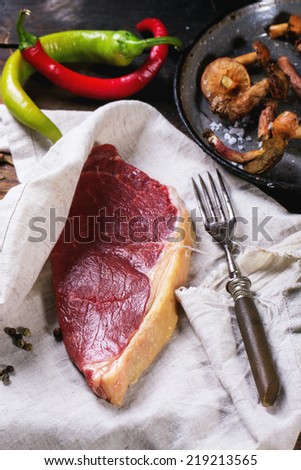 Raw steak in textile served with vegetables and forest mushrooms over old wooden table. See series