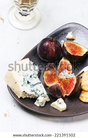 Figs with blue cheese, white wine and crackers on ceramic plate. See series.