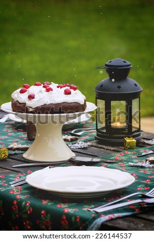 Outdoor Christmas table setting with chocolate cherry cake. See series