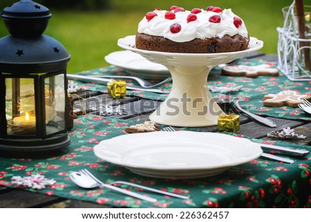 Outdoor Christmas table setting with chocolate cherry cake. See series