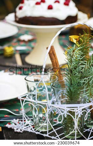 Outdoor Christmas table setting with cinnamon sticks and chocolate cherry cake.