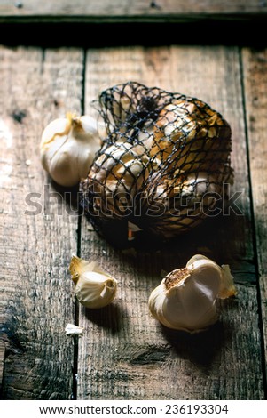 Mesh bag of smoked garlic over wooden background. See series