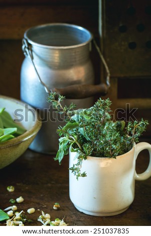 Young sweet peas and mix of herbs rosemary and basil with vintage kitchen utensil over wooden table