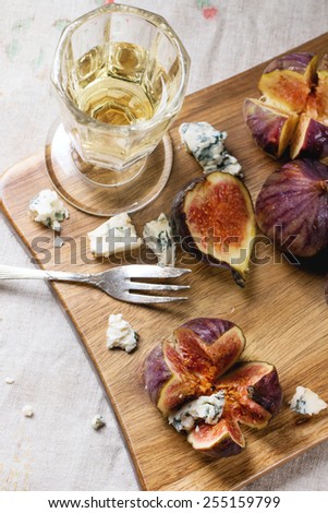 Figs with blue cheese, white wine and crackers on wooden cutting board. See series.
