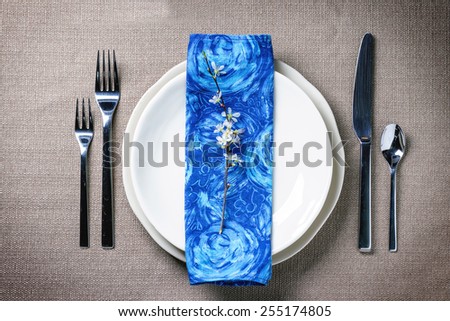 Easter table setting with blue textile napkin, blossom branch and quail eggs. Top view.