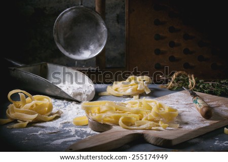 Making homemade pasta linguine on rustic kitchen table with flour, vintage sieve and cutting board. See series.