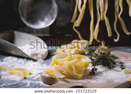 Making homemade pasta linguine on rustic kitchen table with flour, vintage sieve and cutting board. See series