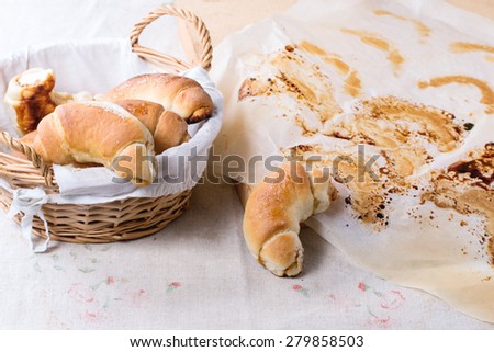 Fresh homemade baked bagels in basket and on baking paper over light gray tablecloth