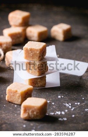 Fudge candy and caramel on baking paper, served over dark background.