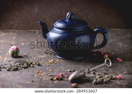 Blue ceramic teapot served with black and green tea lives over dark background. Chinese inscription on teapot - traditional tea drinking