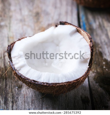 Broken coconut on old wooden background. Square image