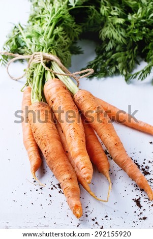 Bundle of carrots with soil over light blue wooden background