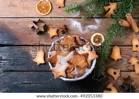 Homemade Christmas shortbread star shape sugar cookies different size with sugar powder, cinnamon, green fir tree and cookie cutters on old wooden surface. Christmas treats. Overhead view