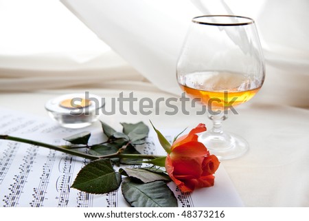 beautiful red rose with music notes, glass and burning candle
