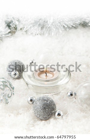 Silver christmas balls with a burning candle on the snow