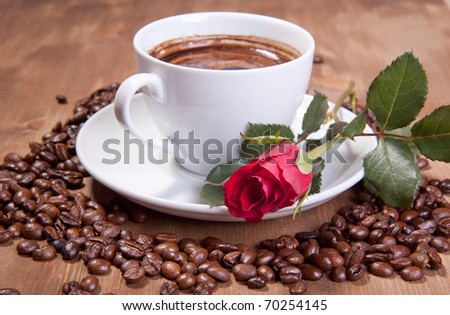 White cup of black coffee with coffee beans and red rose