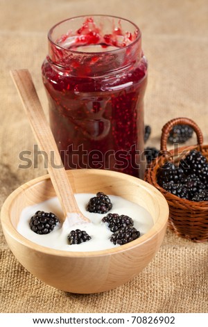 Wooden bowl of Yogurt and blackberries with pot of jam on sackcloth