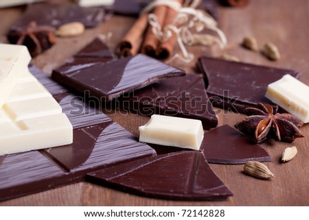 Chopped black and white chocolate with cinnamon, anise and cardamom on wooden table
