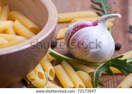 Bowl of pasta with salad and garlic on wooden table