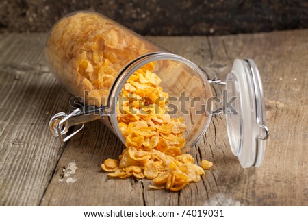 Golden corn flakes from plastic jar on old wooden table