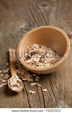 Wooden bowl of dry muesli and wooden spoon on old wooden desk