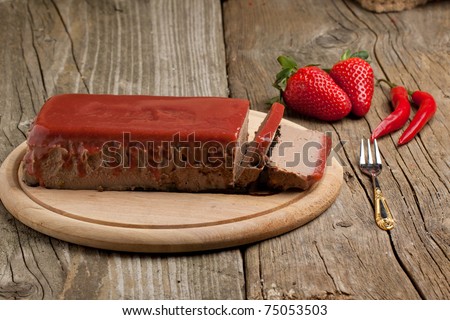 Pate Appetizer with strawberry jelly, fresh strawberry and red hot chili peppers on wooden desk over wooden background