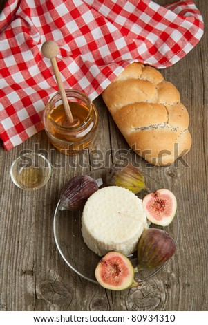 Plate with white cheese and fresh figs with honey and bread on old wooden table