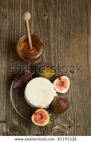 Top view plate with white cheese and fresh figs with honey on old wooden table