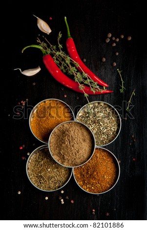 Top view on red hot chili peppers and mix of spices on black table