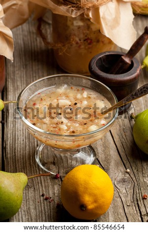 Pear jam in glass vase and fresh pears on old wooden table