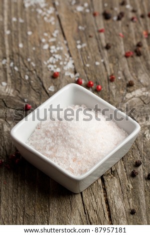 White plate of rose sea salt and pepper on old wooden table